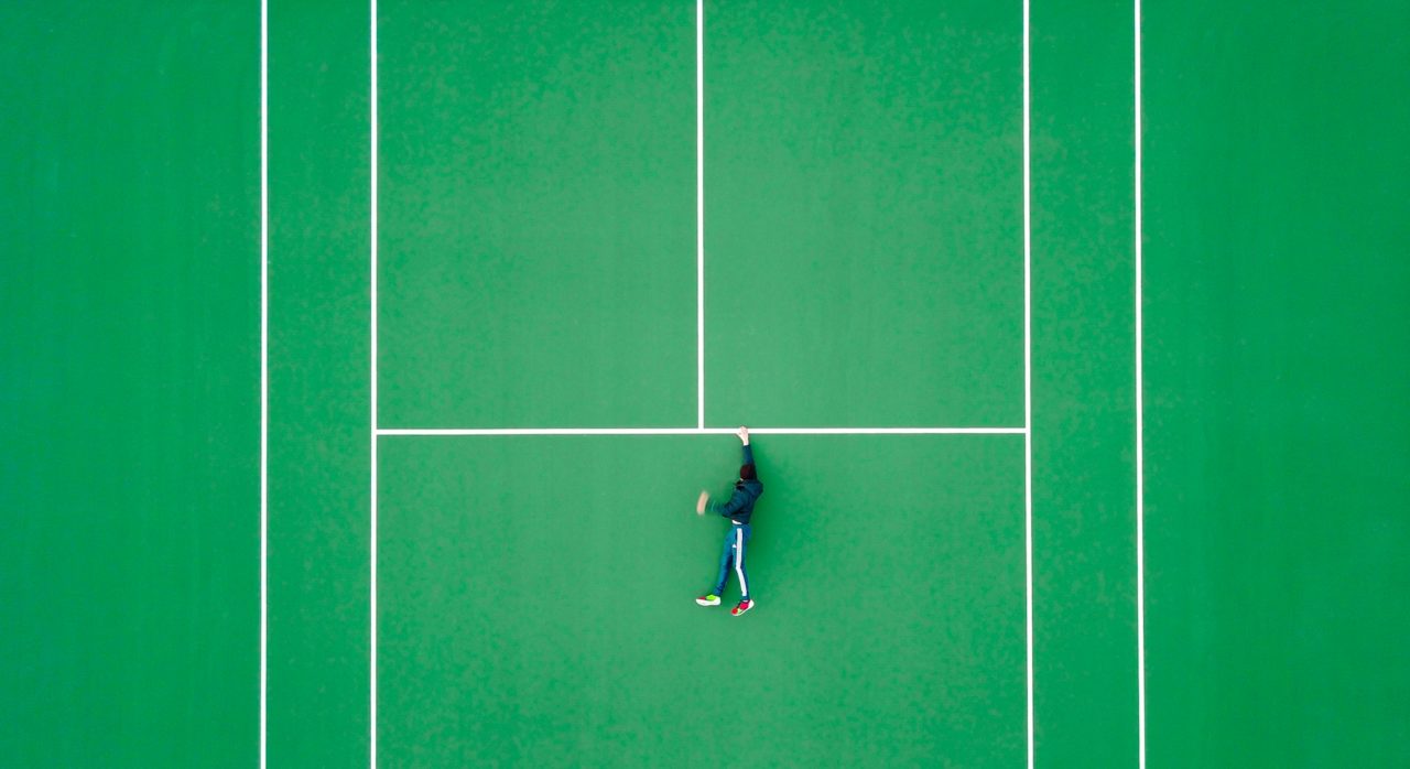 giocatore sdraiato su campo da tennis a fondo verde